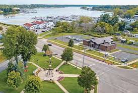 An aerial view of a forested Michigan lake with communities along the shore, like White Lake shared by Whitehall and Montague.