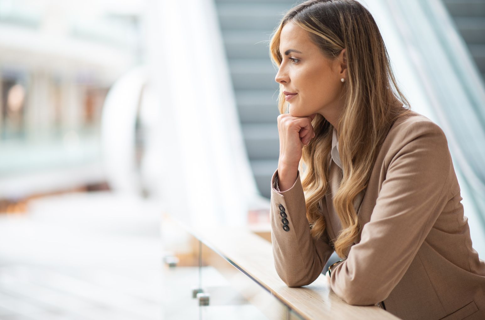 Woman in desk, leaning on a chin and looking thoughtful in natural light