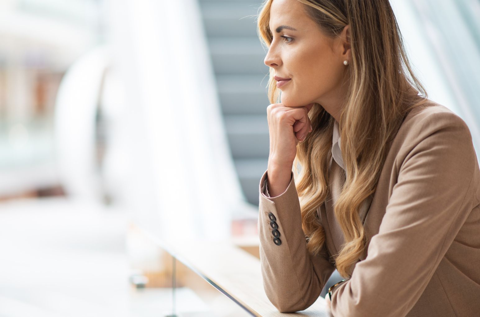 Woman in desk, leaning on a chin and looking thoughtful in natural light
