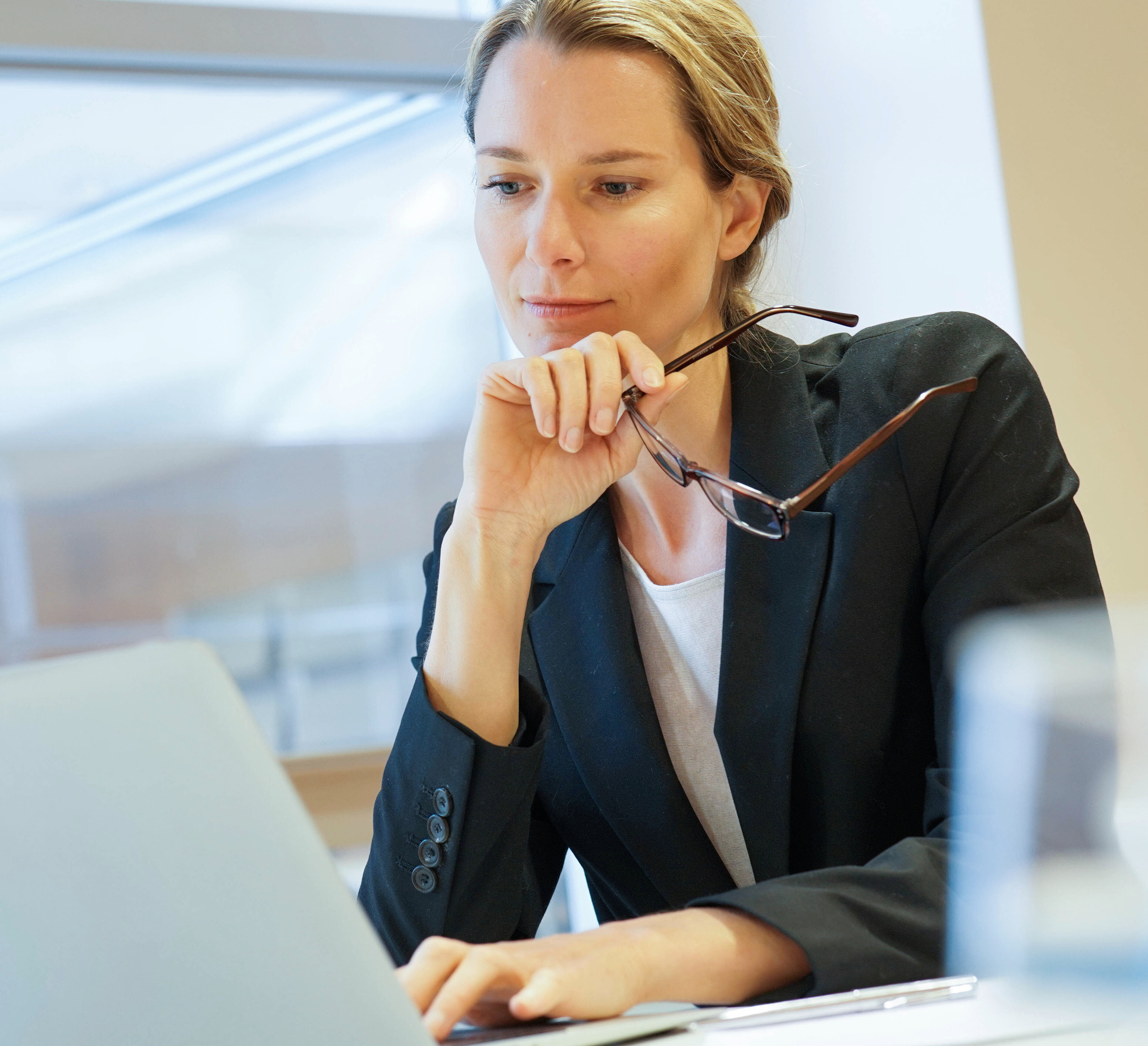 Woman in desk, leaning on a chin and looking thoughtful in natural light