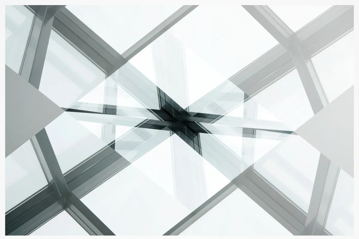 Abstract glass and steel architectural framework converging at a central structural junction.
