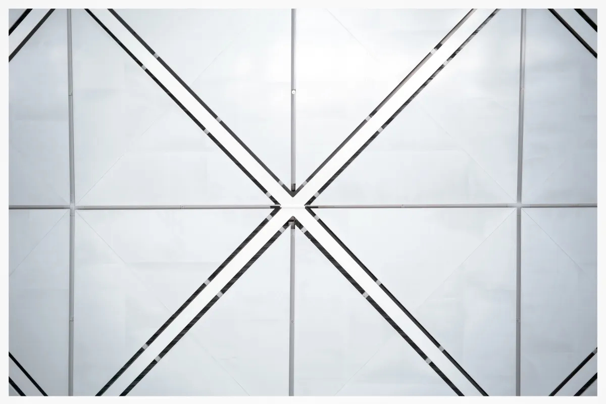 Minimal glass and steel architectural grid with diagonal braces converging at the center.