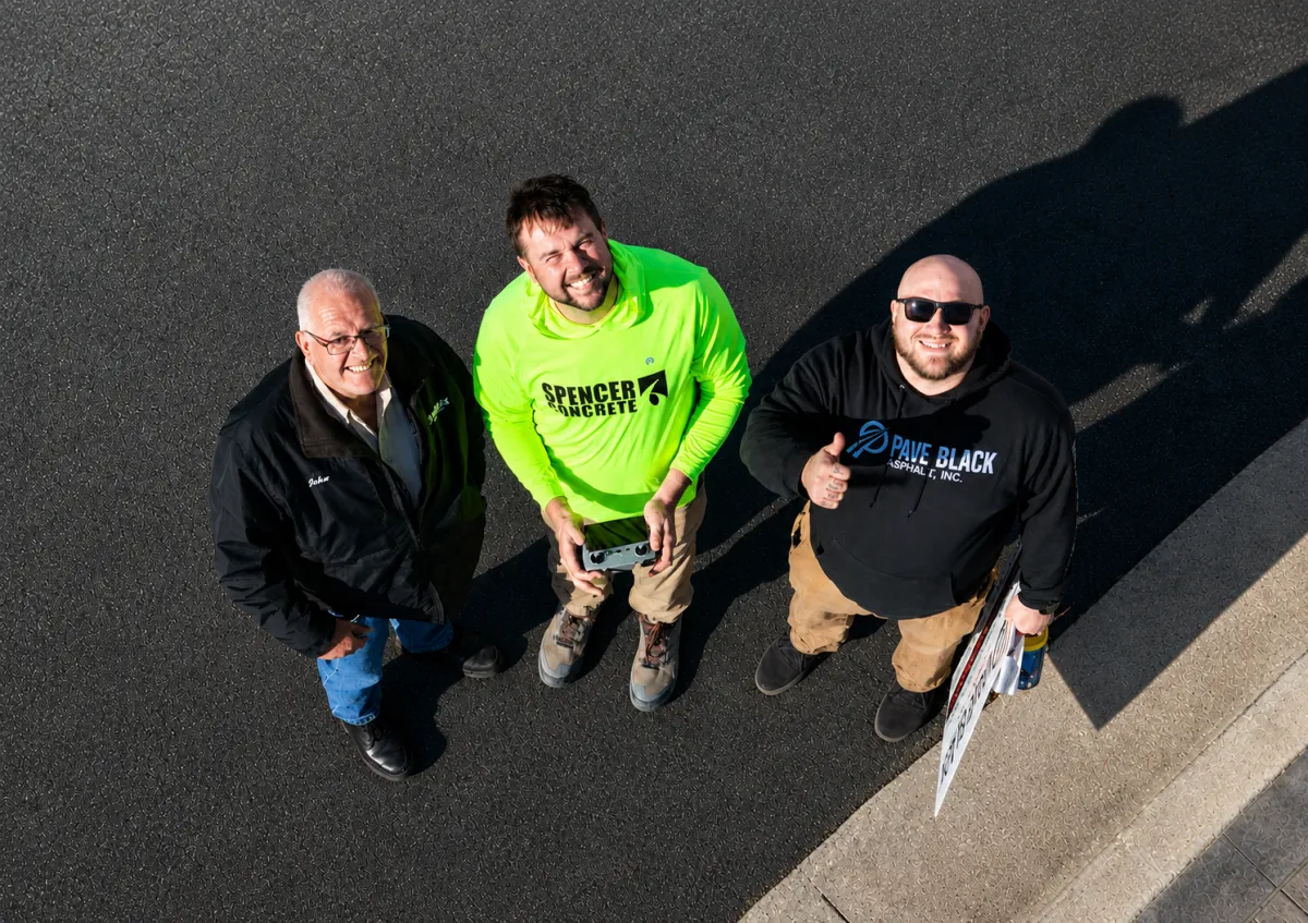 Main Executive team members from Spencer Concrete and Pave Black Asphalt standing together on freshly paved asphalt in Appleton, Wisconsin.