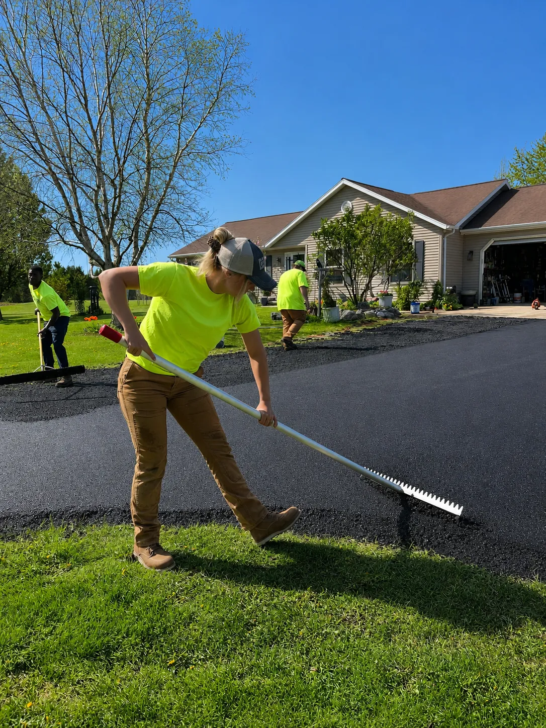 Pavement laborer raking fresh asphalt on a residential driveway in the Fox Valley, Wisconsin