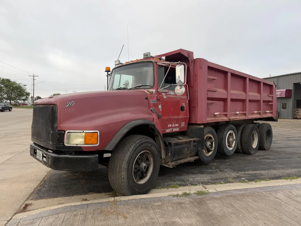 Used heavy-duty dump truck with red steel dump body and tandem rear axles for sale