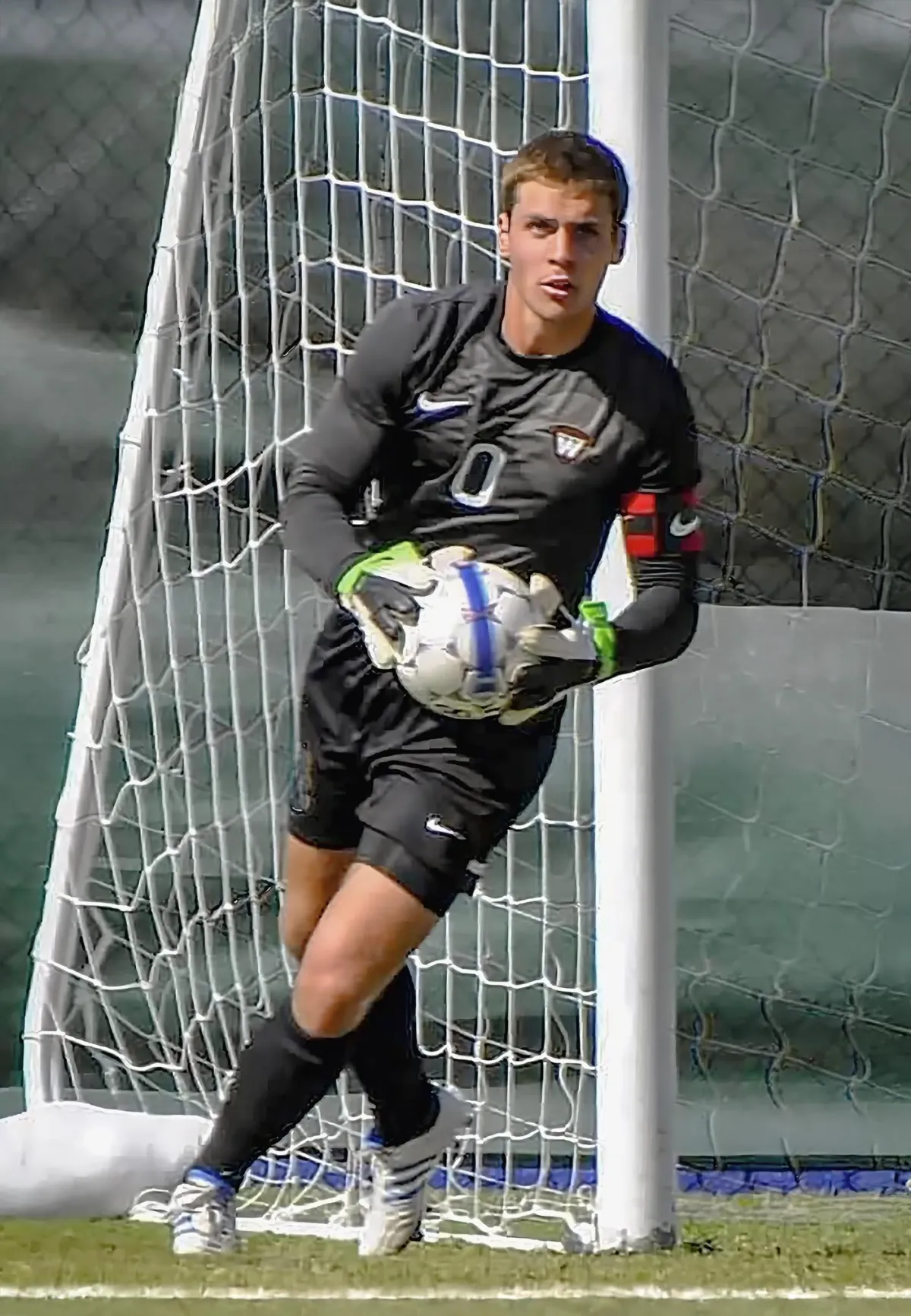 Coach Matthew McNab demonstrates goalkeeping technique on the field, instructing in live training.