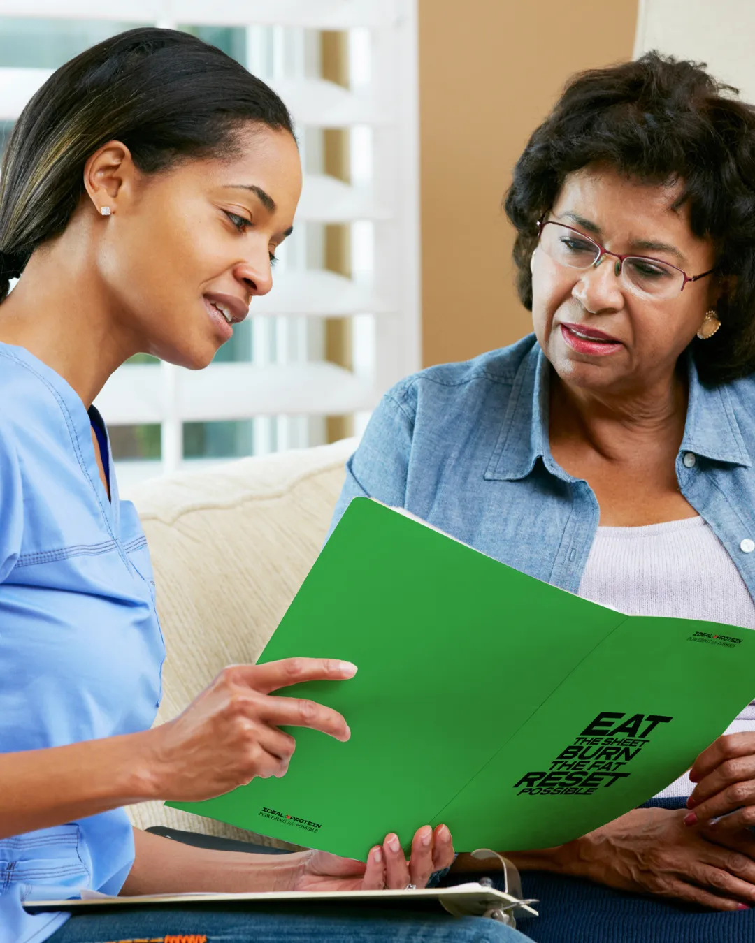 A certified Ideal Protein coach reviews the program guide with a client during a one-on-one coaching session