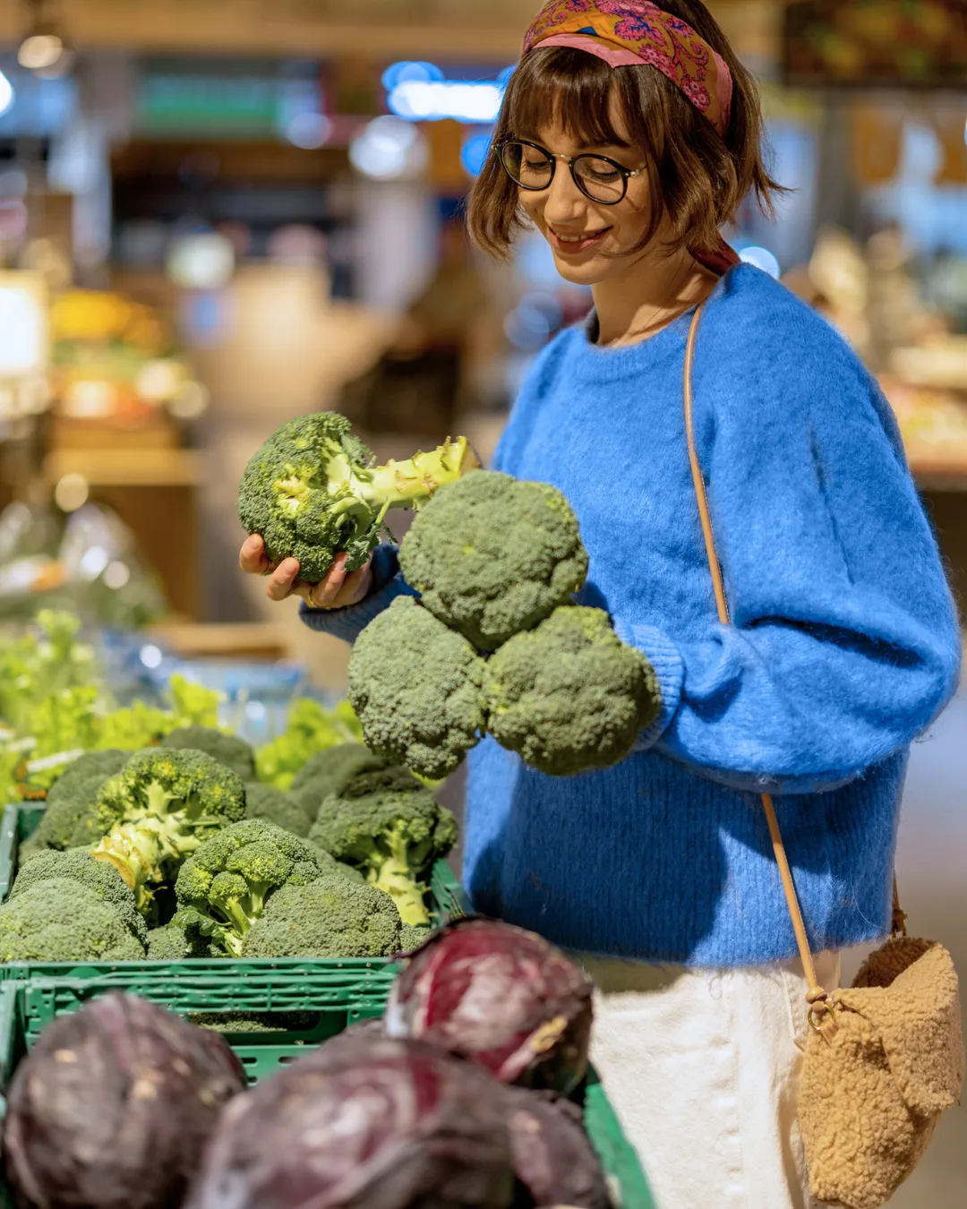 A woman selects fresh vegetables at a grocery store, building healthy food habits during weight loss stabilization
