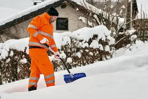 Worker shoveling residential driveway during snow removal service in Davenport