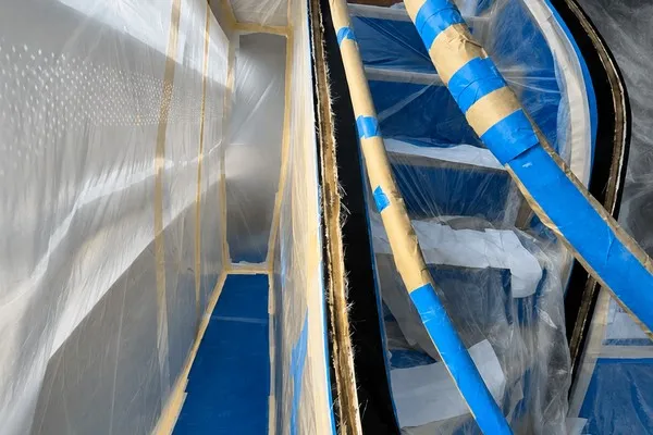 Yacht interior staircase with seams ground out ready for repair, surrounding areas masked and sheeted in protective film