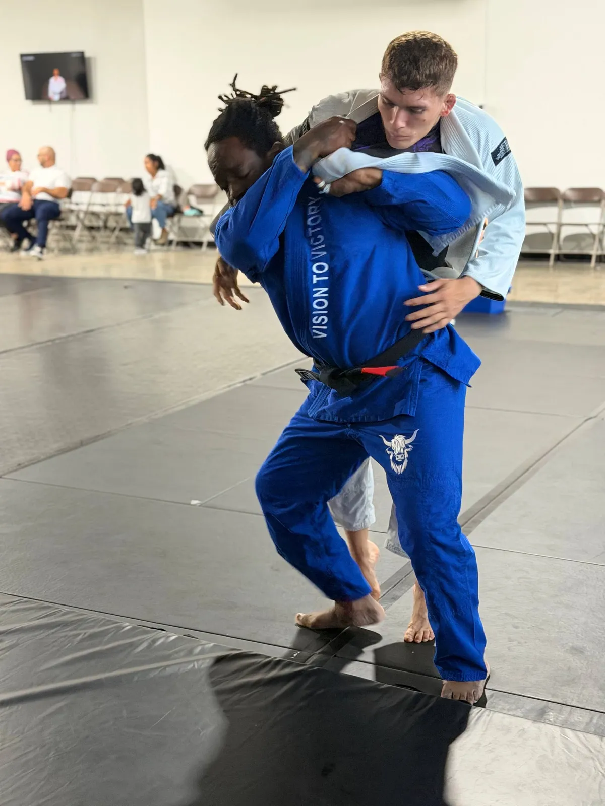 Confident adult martial arts student receiving personalized guidance from an instructor in a clean, modern training academy
