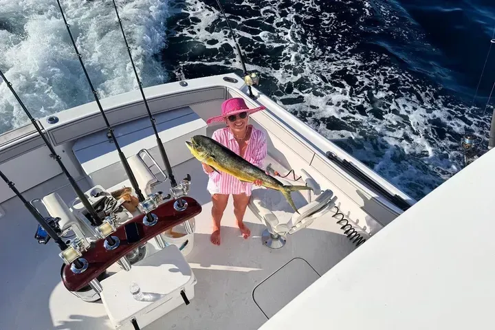Guest showing a mahi-mahi on the back deck with trolling rods during a 3/4-day private charter in Pompano Beach.