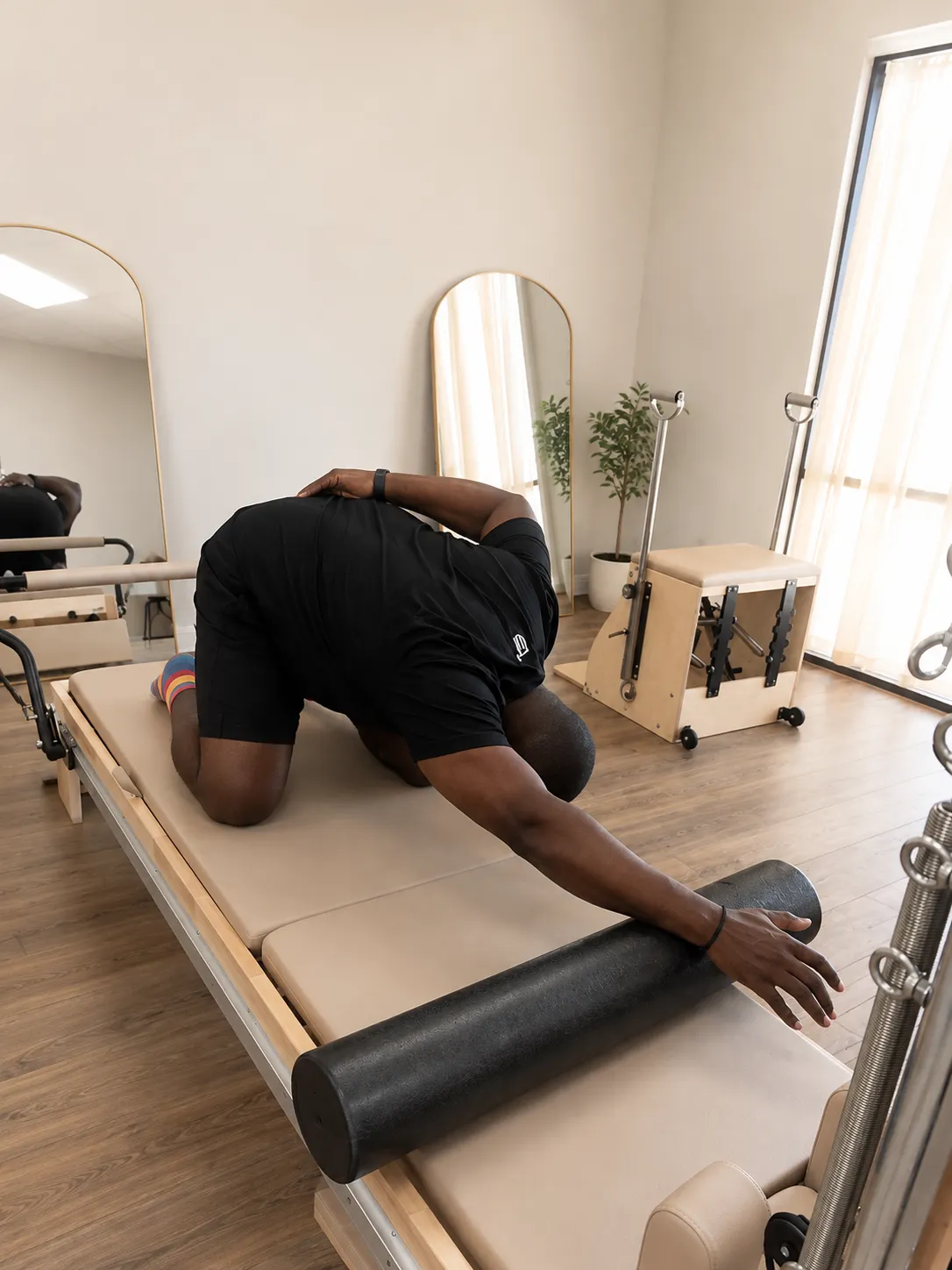 Dedicated client practicing classical Pilates on a reformer in a bright, minimalist studio