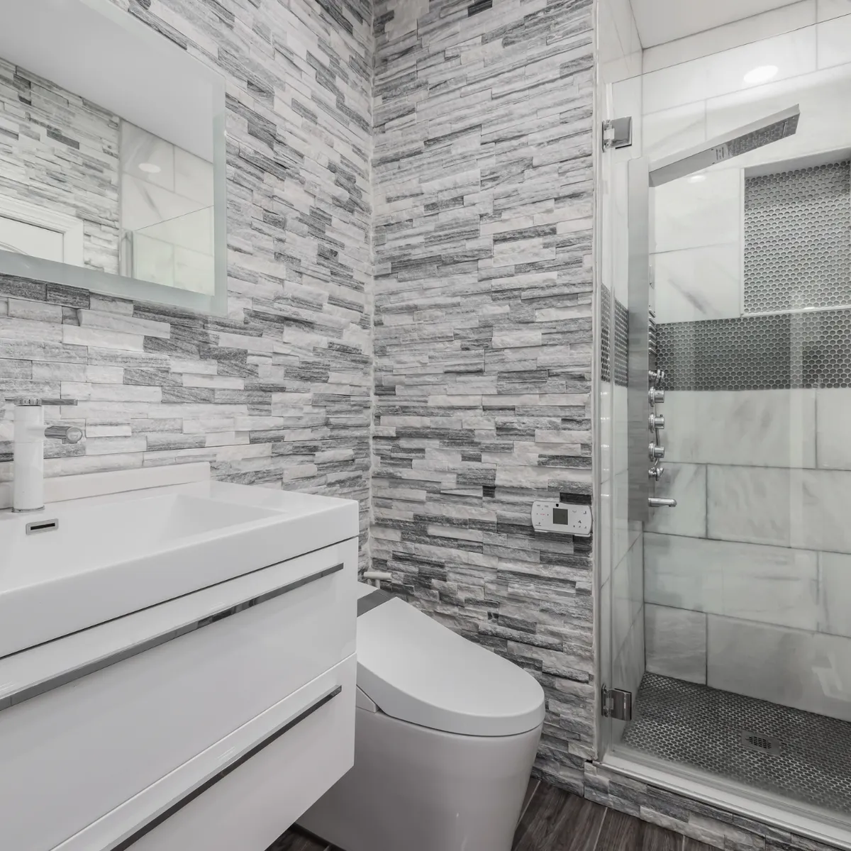 Bathroom renovation in the Houston area (Katy, Texas) with a tiled walk-in shower, modern vanity, and sleek gray accent walls.
