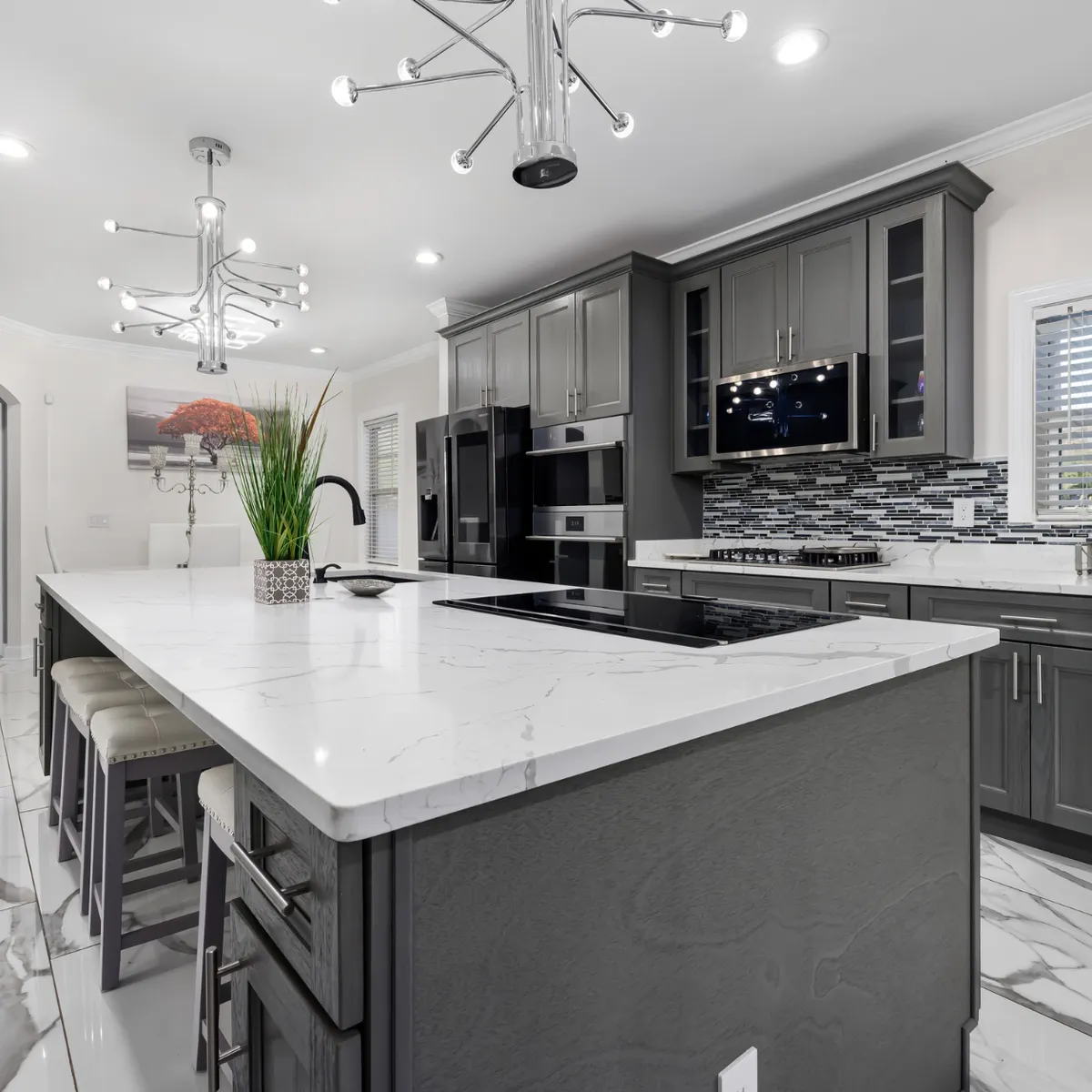 Houston-area kitchen remodel (Katy, Texas) with a large island, quartz countertops, gray cabinetry, and modern pendant lighting.