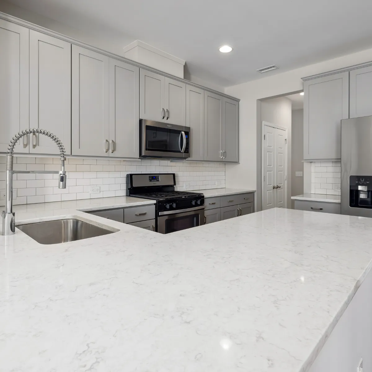 Bright kitchen remodeling project in the Houston area (Katy, Texas) with white cabinetry, quartz countertops, and stainless steel appliances.