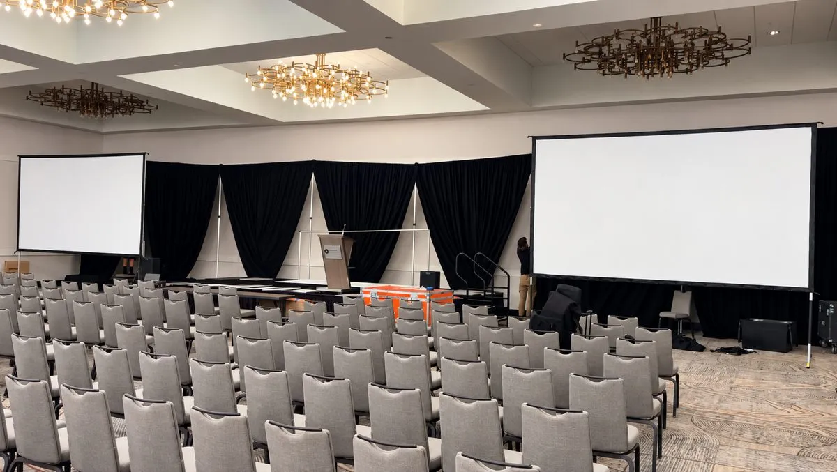 Two projection screens and stage drape set in an Austin hotel ballroom