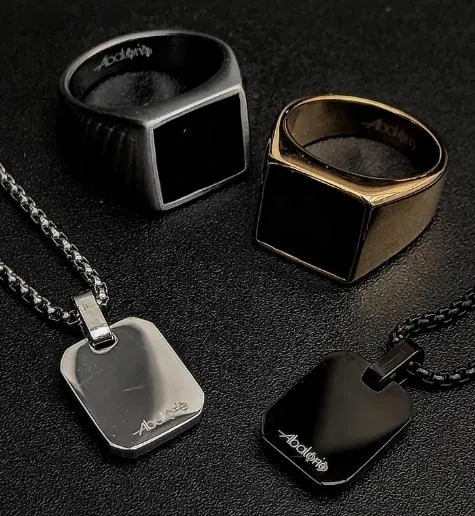 A masculine hand wearing a black leather bracelet with gold and silver metal accents, urban background