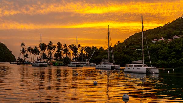 Golden sunset over Marigot Bay in Saint Lucia with sailboats anchored in the calm Caribbean harbor