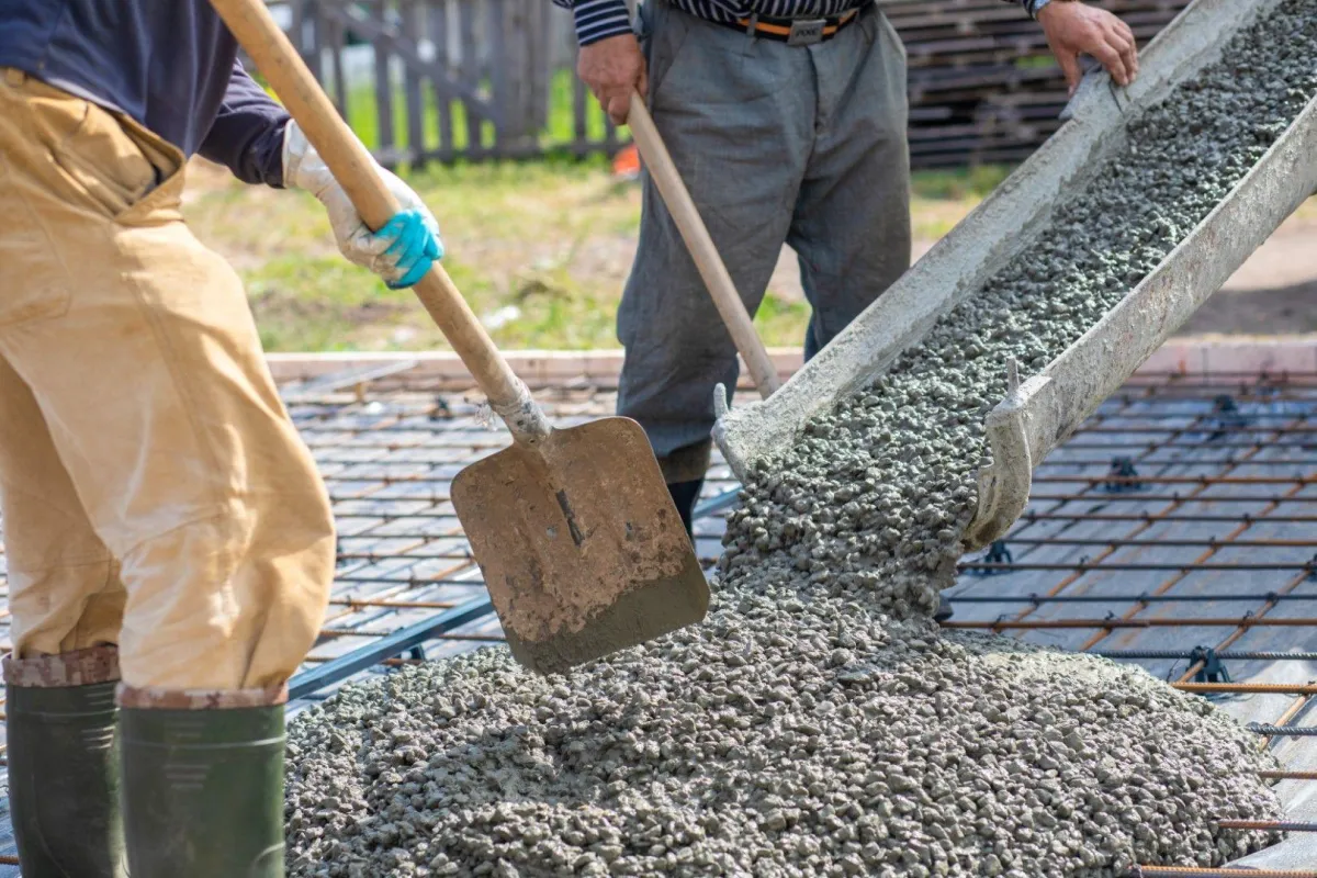 contractors pouring concrete on rebars and using shovel
