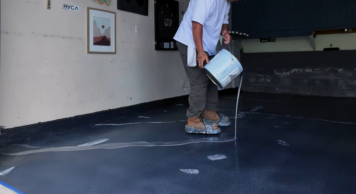 pouring white epoxy over a garage floor