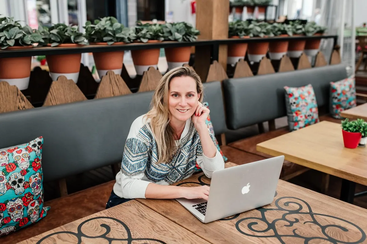 Chanelle Segerius-Bruce smiling at a café laptop, using storytelling in her marketing