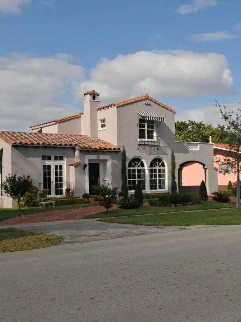 Remodeled home exterior in Garland TX featuring stucco siding, arched windows, and updated landscaping in a residential neighborhood