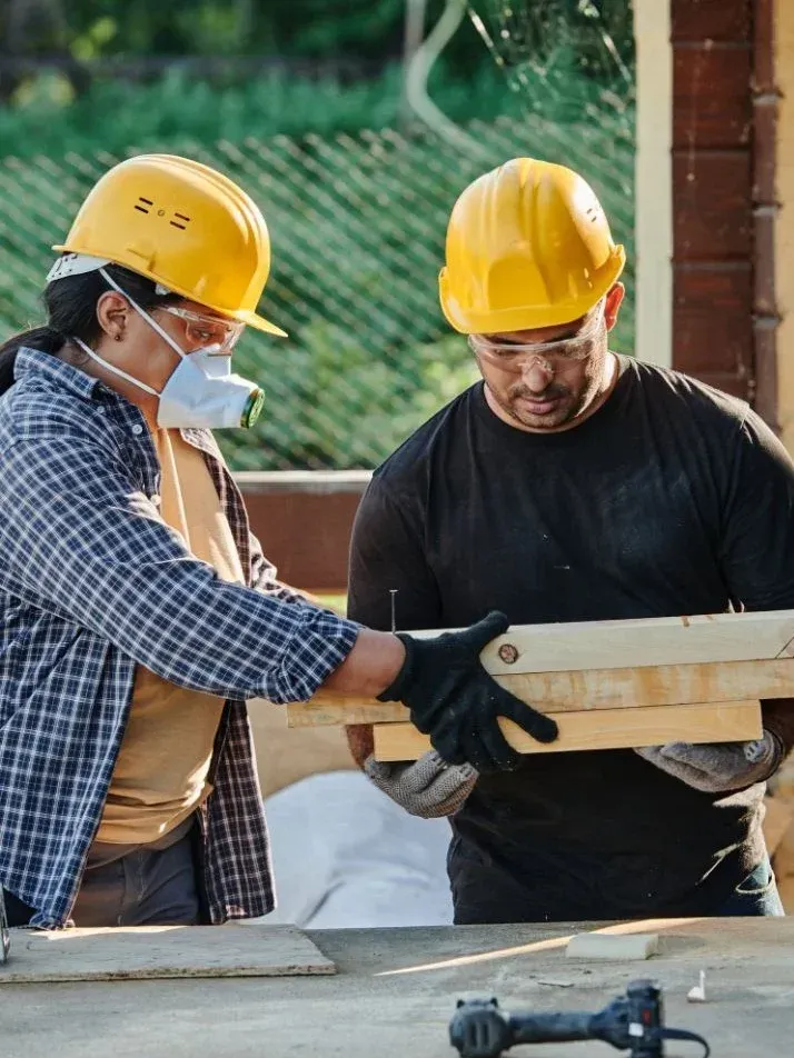 Two general contractors in Allen, TX wearing hard hats and safety gear working together on a construction project.
