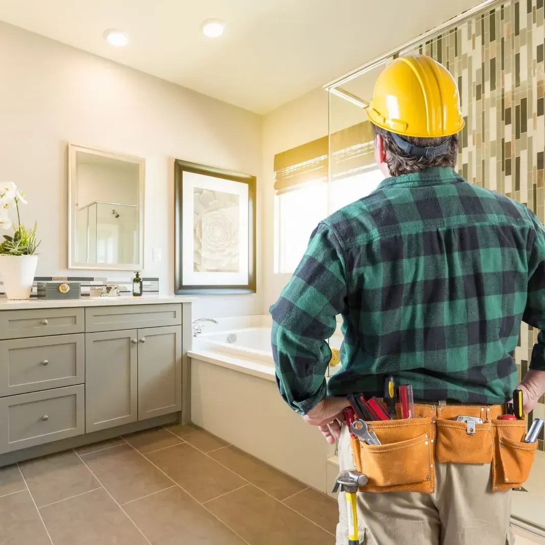 Contractor inspecting a finished bathroom remodel in Addison, TX with modern cabinets, mirrors, and a soaking tub