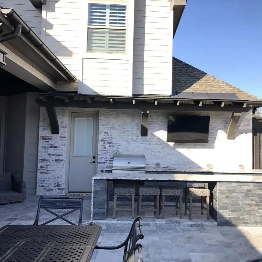 Outdoor kitchen and patio space in Denton TX with built-in grill, bar seating, and entertainment area