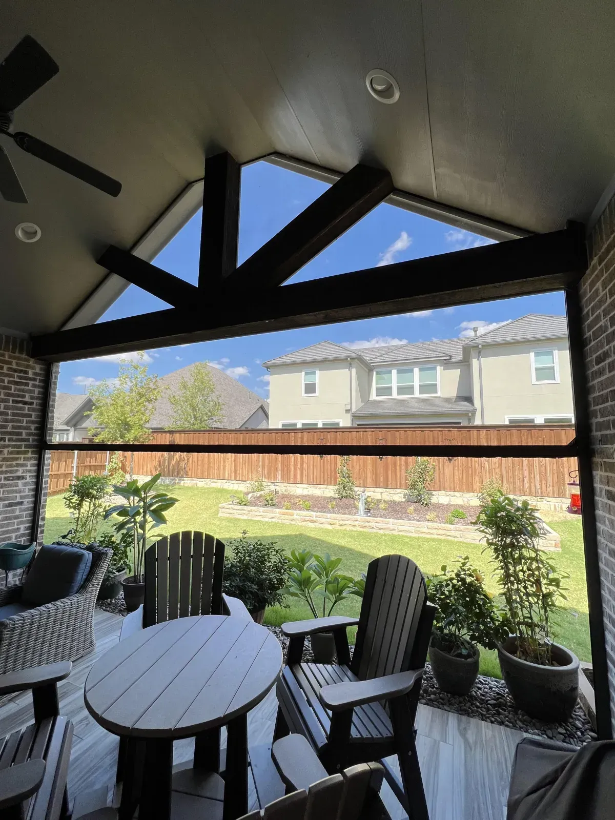 Custom gable patio cover in Carrollton, TX with exposed beams, ceiling fan, and full roof protection.