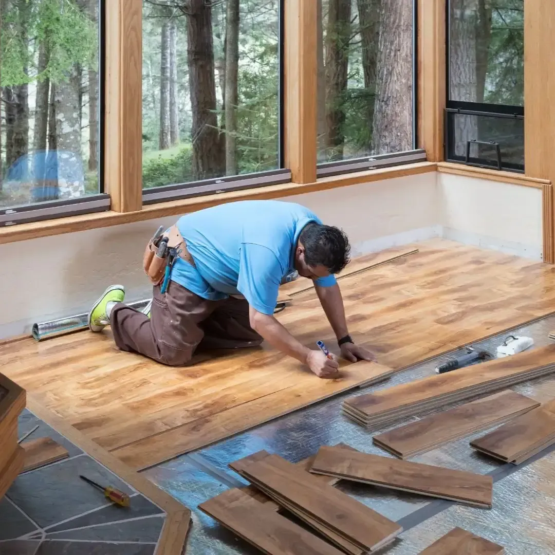 Flooring installation in Sachse TX with contractor laying hardwood planks in a living room.