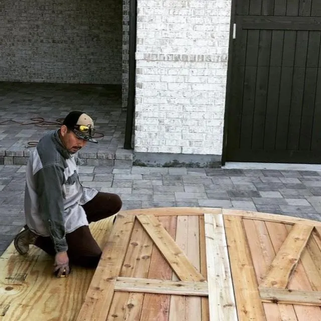 Texas Woodpeckers craftsman installing a custom cedar gate on a paver driveway in Rowlett, TX.