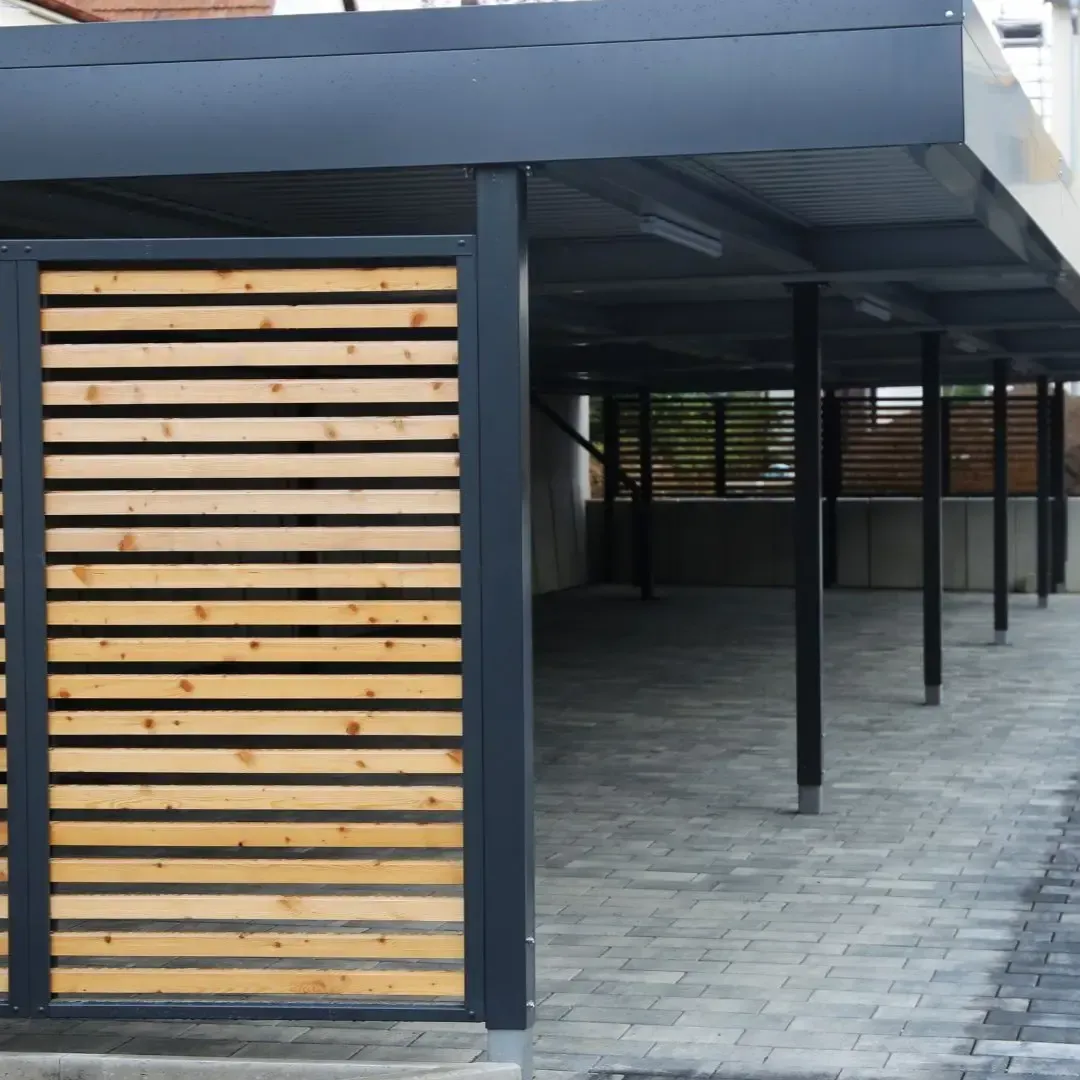 Custom carport in Rowlett TX with metal frame, wood slat privacy wall, and paver driveway built by Texas Woodpeckers.