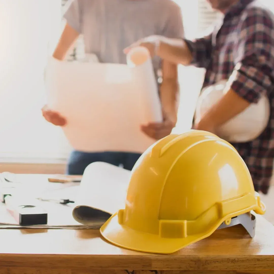General contractor jobsite prep in Coppell with yellow hard hat and plans on table