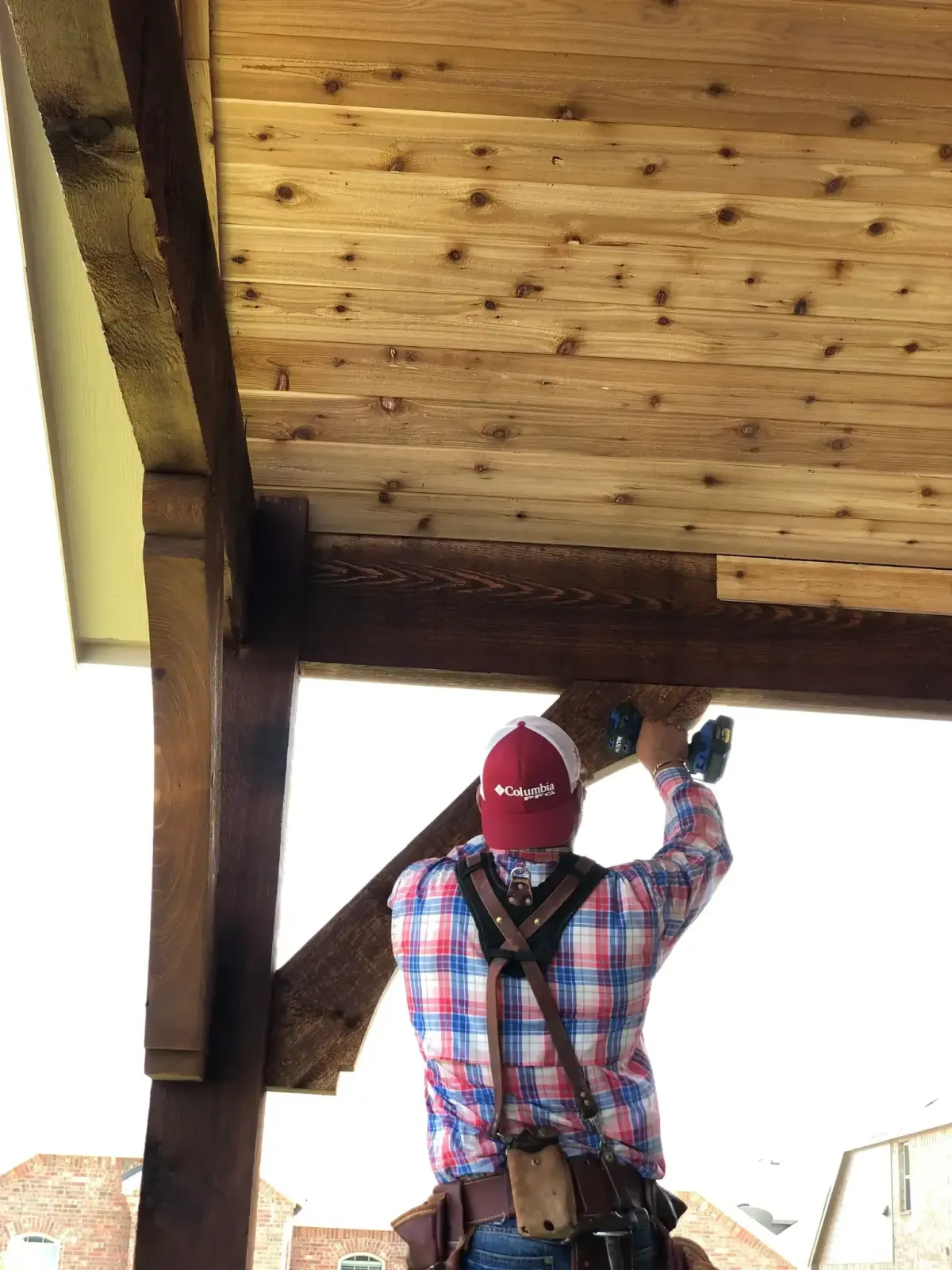 Carpenter installing cedar tongue-and-groove ceiling on a patio cover in Farmers Branch, TX