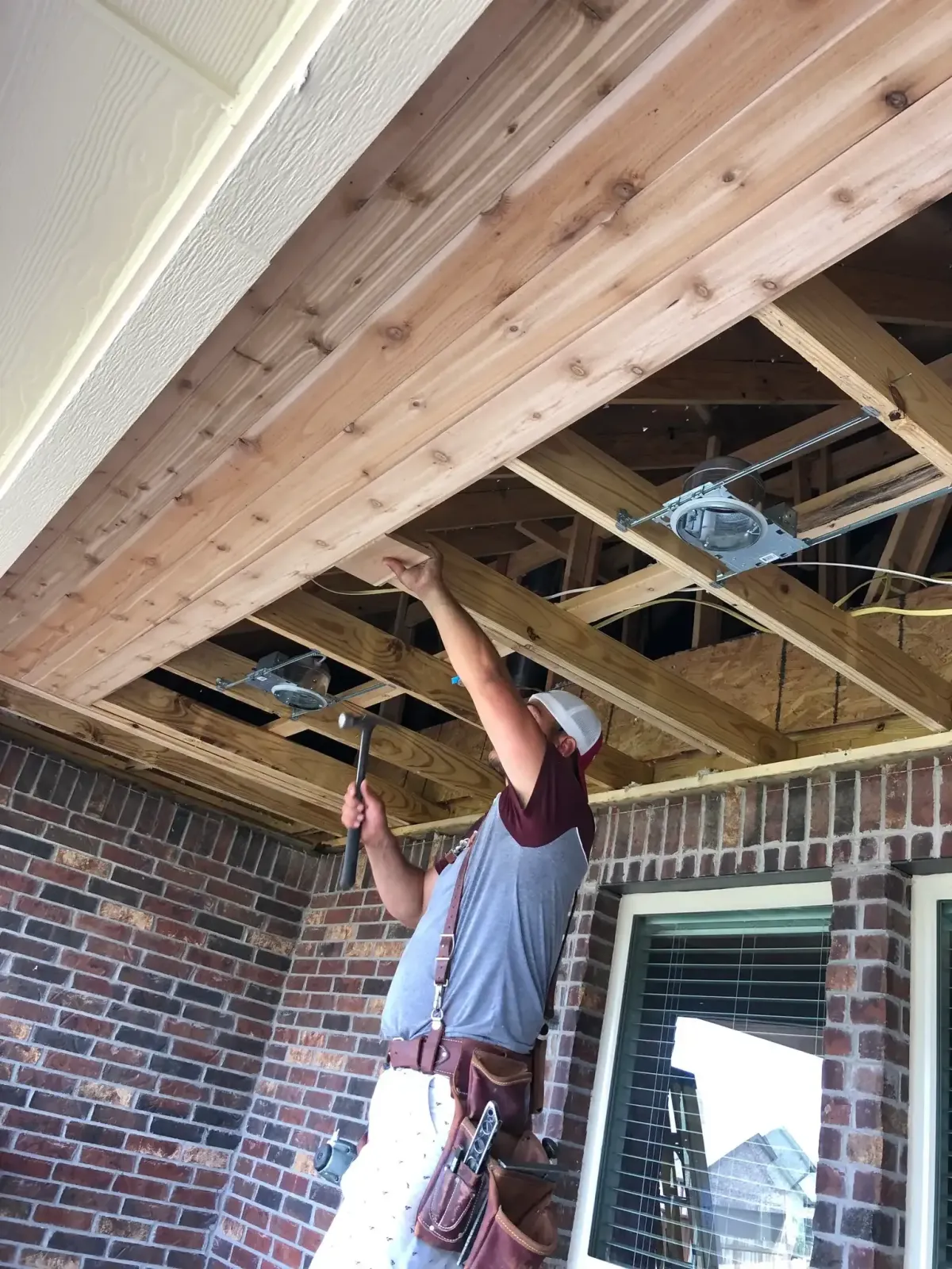 Contractor building a custom patio cover in Lewisville TX with wood framing and ceiling installation