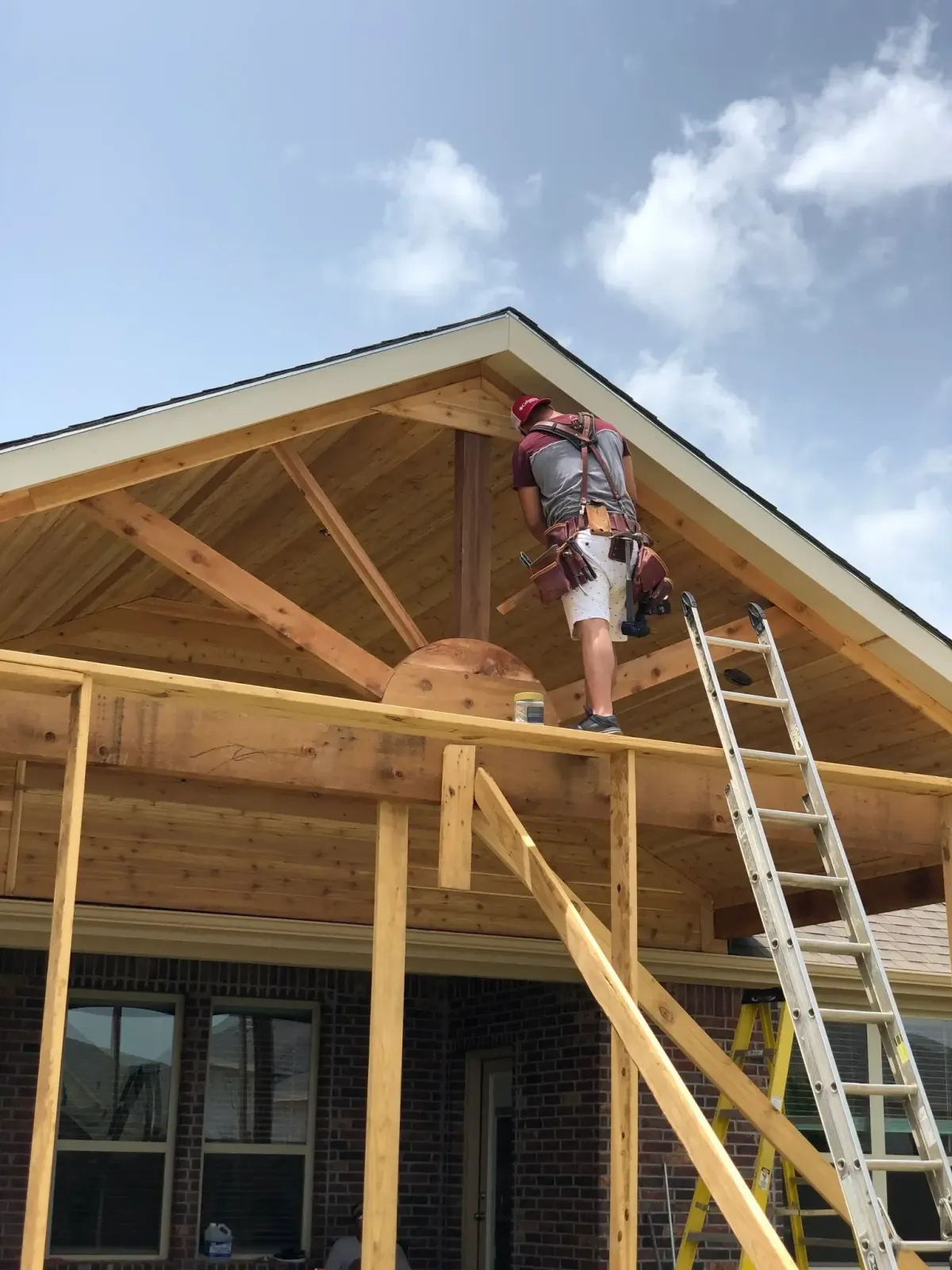 Contractor building a gable roof patio cover with cedar beams in Highland Village TX
