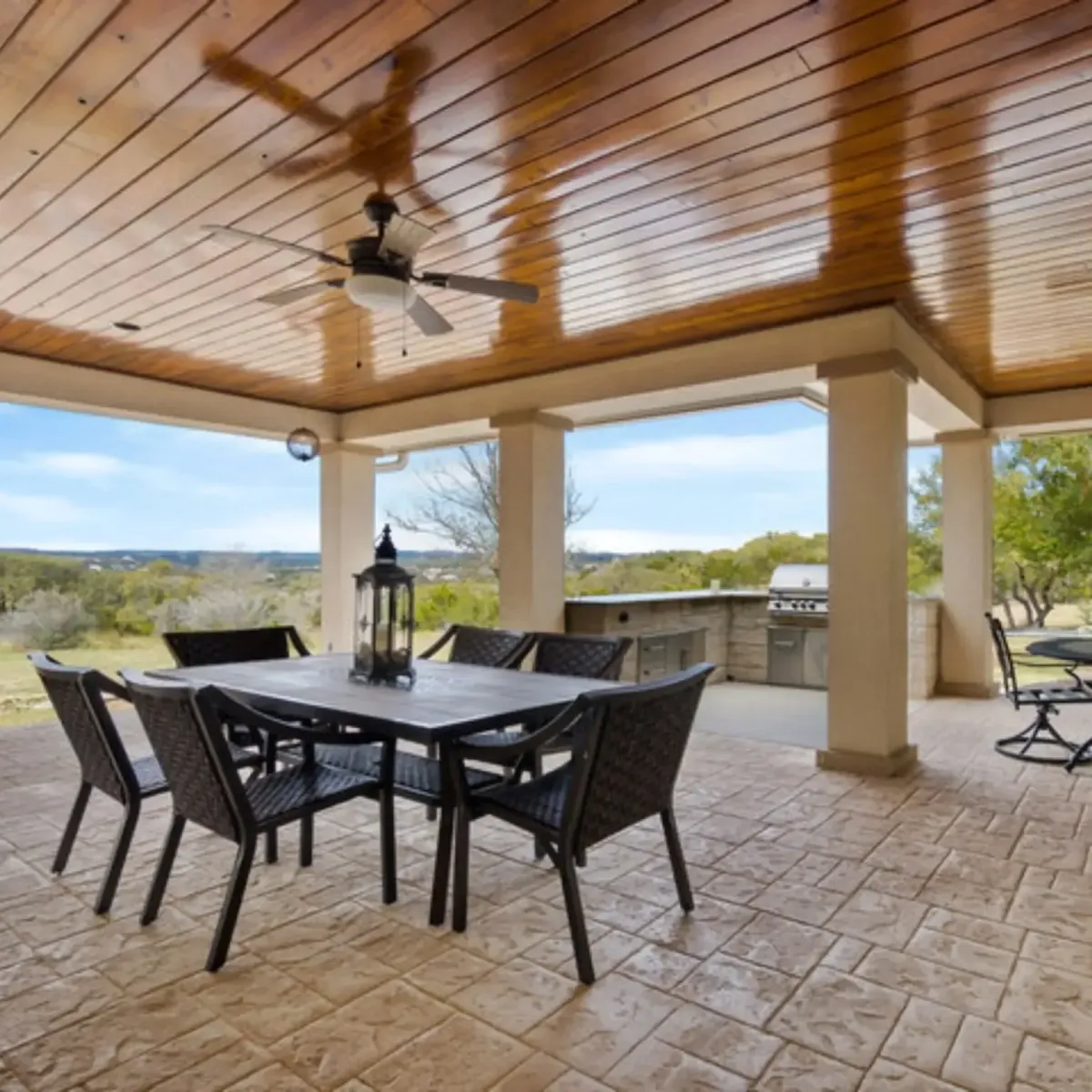 Covered patio in Highland Village TX with wood ceiling, ceiling fans, outdoor kitchen, and stamped concrete floor