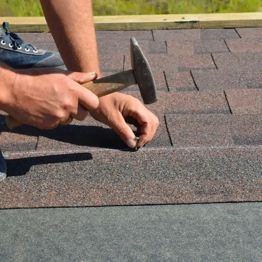 roofer repairing asphalt shingles on a home in Carrollton TX