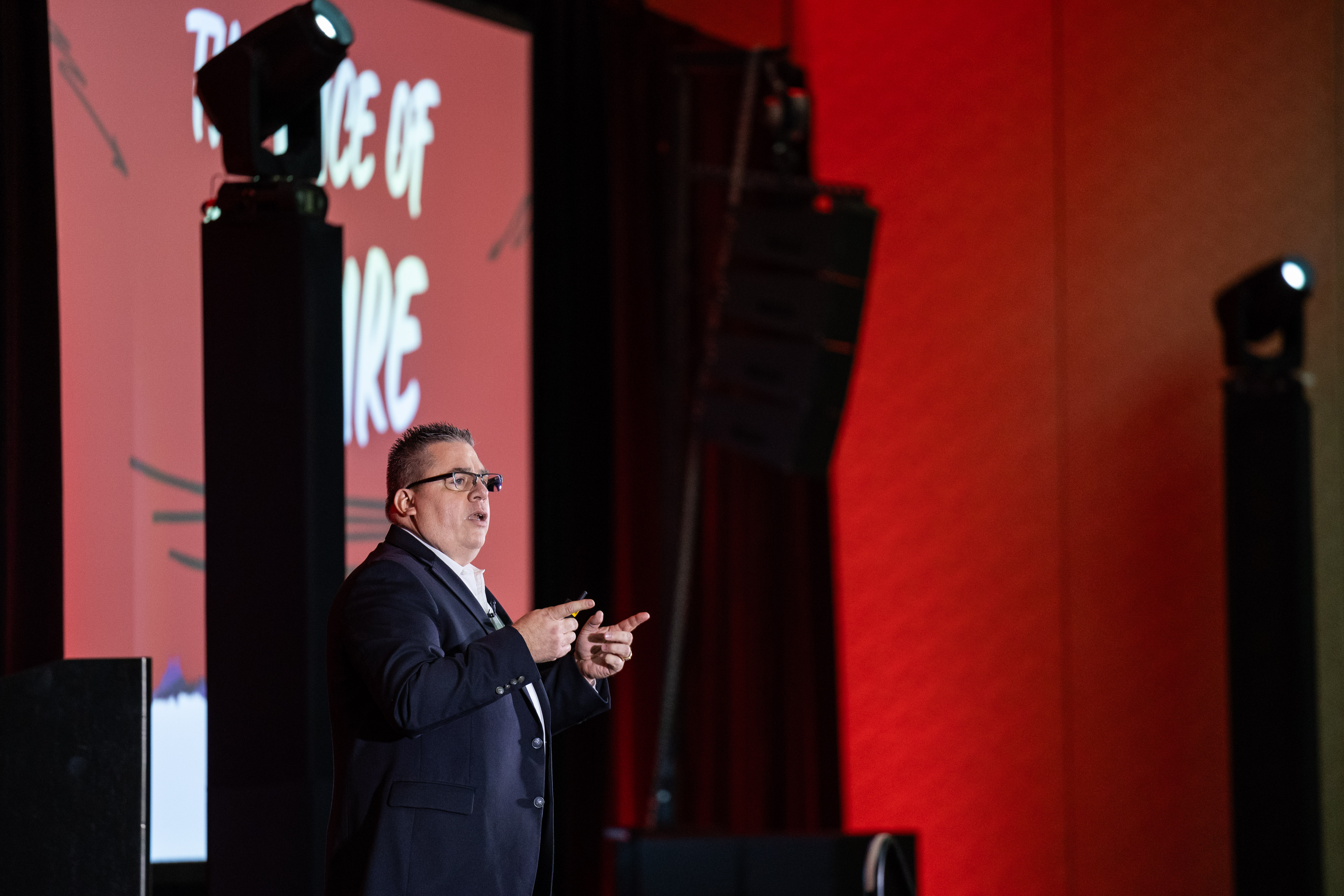 Gary L. Barker delivering a keynote presentation on stage at a corporate leadership event.