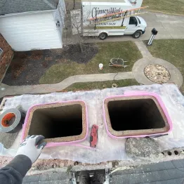 Chimney repair technician fixing cracked bricks and flue liner on residential chimney in Cincinnati, Ohio