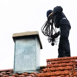 Certified chimney sweep cleaning a fireplace chimney in Cincinnati home to ensure safe and efficient operation
