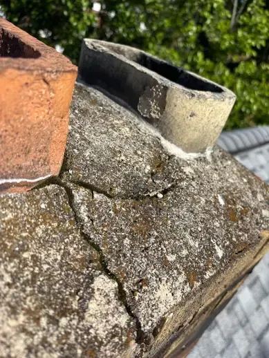 Exterior chimney on a Cincinnati house showing a visible crack just below the chimney cap, indicating structural damage