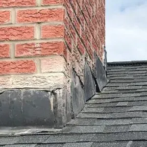 A brick chimney in a Cincinnati home showing damaged flashing with lifted metal and visible gaps, a common issue due to Midwest weather conditions