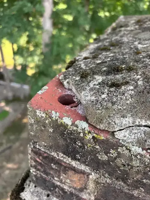 Chimney crown on a Cincinnati home showing severe cracks and mold growth, indicating water damage and urgent need for professional repair by ChimneyWorks.