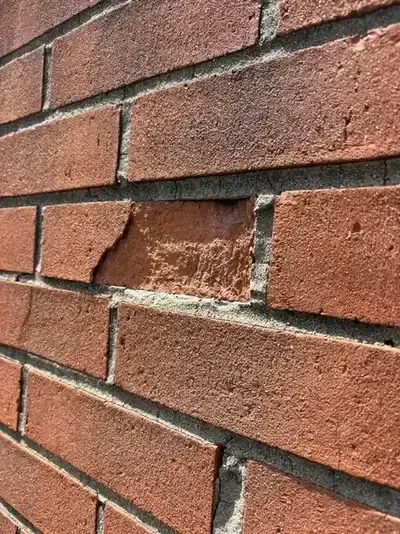 Brick chimney with deteriorating mortar joints and crumbling bricks on a Cincinnati home—signs it needs tuckpointing to prevent water intrusion and chimney damage.