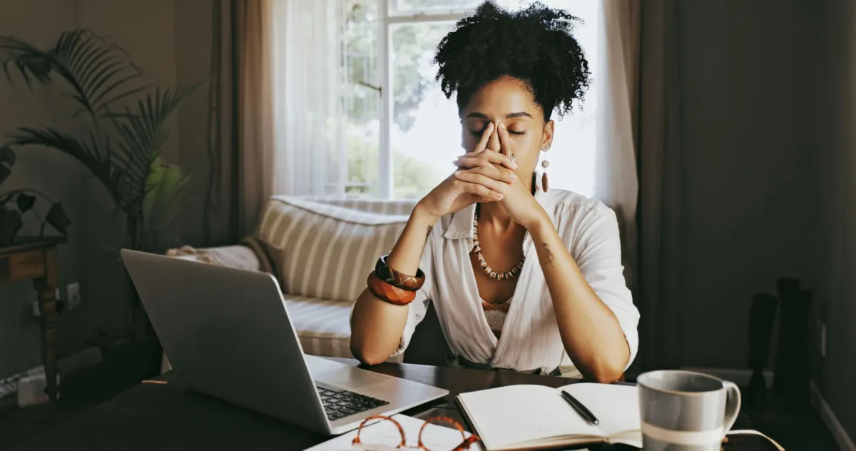 woman is sitting at a desk overwhelmed with anxiety