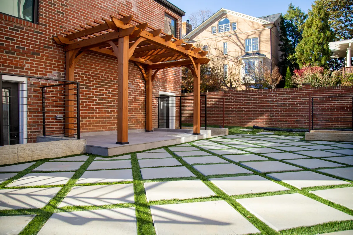 Aerial view of a newly completed suburban backyard patio and planting beds, evening warm light, photorealistic 3:2 framing highlighting layout and flow.