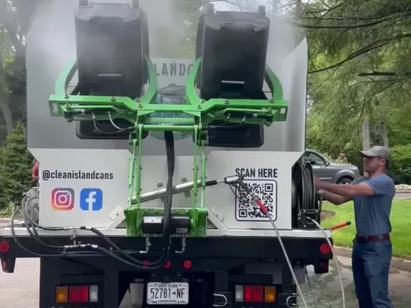 Rear view of Clean Island Cans truck actively sanitizing trash bins with hot water and steam.